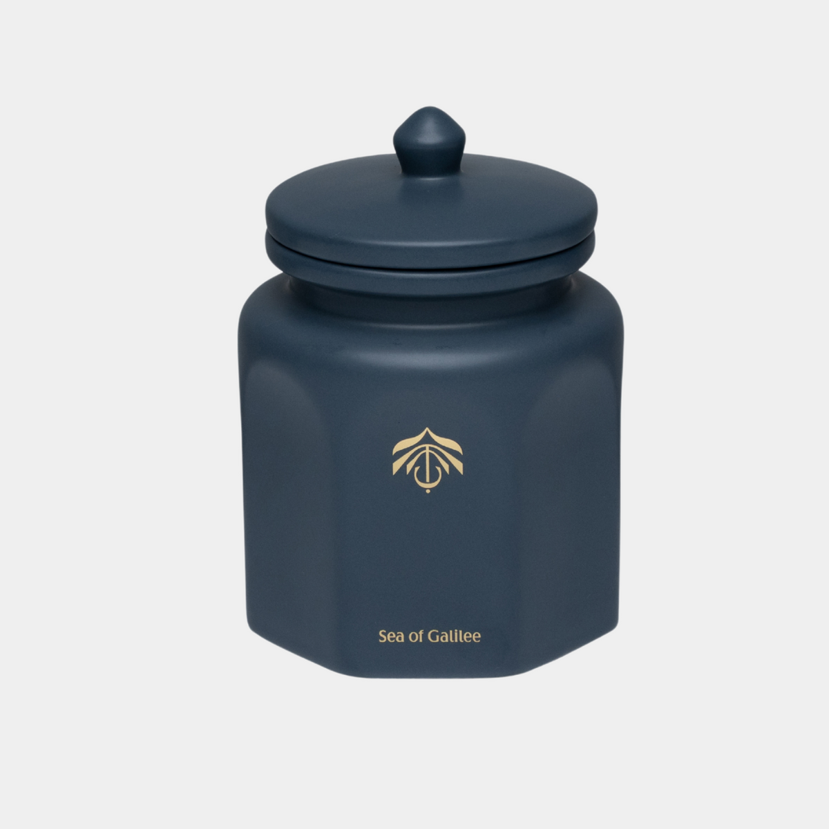 A dark navy blue hexagonal ceramic canister with a matching lid, featuring a gold Sea of Galilee logo and name on the front, set against a light gray background.