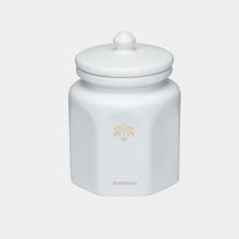 A white hexagonal ceramic candle vessel with a matching lid and a small gold printed logo and the word 'Bethlehem' on the front, set against a light gray background.