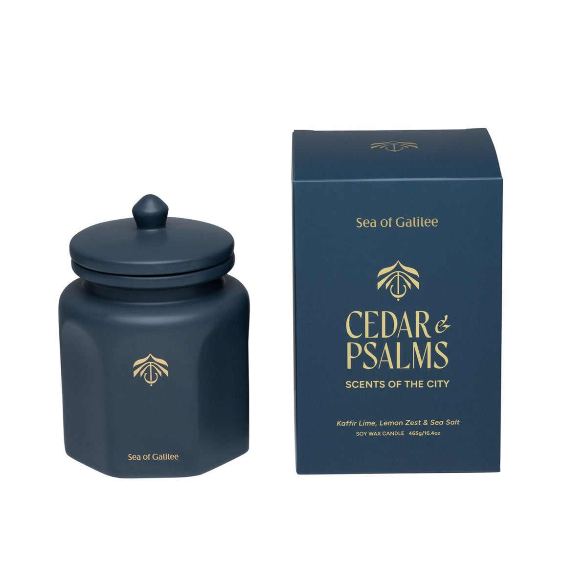 A dark navy blue glass jar candle with a matching lid and a matching dark blue box, both featuring gold lettering that reads 'Sea of Galilee' and 'CEDAR & PSALMS SCENTS OF THE CITY'.